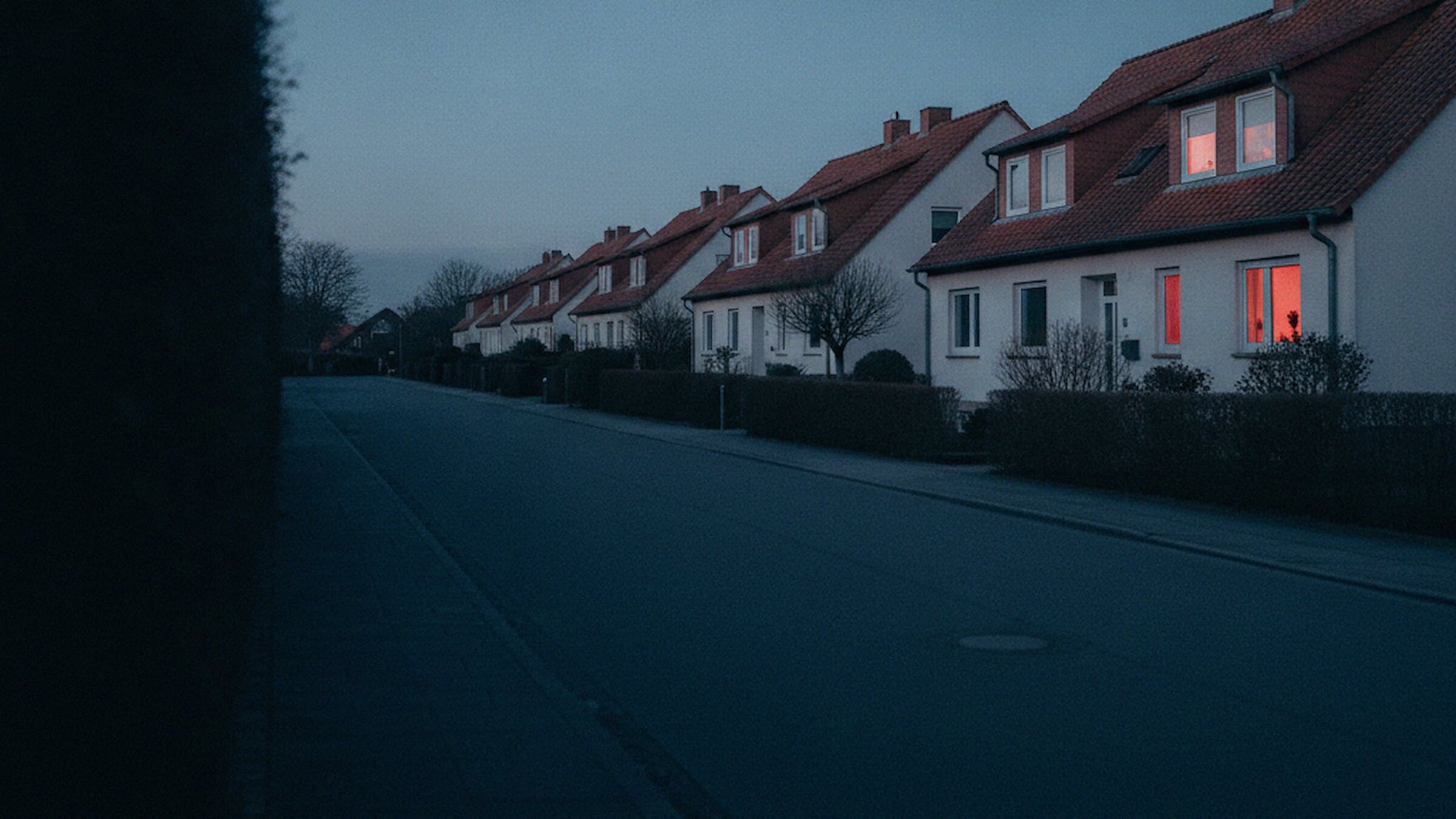 Reihe freistehender Wohnhäuser an einer ruhigen Strasse in der Abenddämmerung